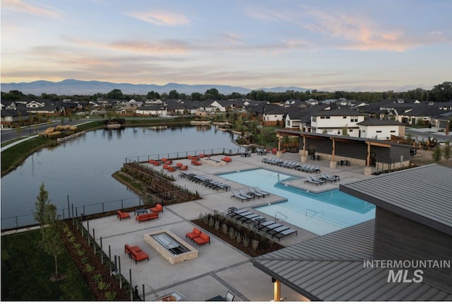 community pool featuring a patio area, a residential view, a water and mountain view, and fence