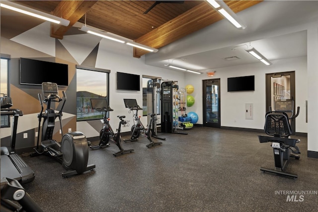 gym featuring wooden ceiling, beam ceiling, and baseboards