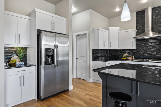 3924 E Forked Deer St, Boise, ID 83716 - kitchen with stainless steel fridge with ice dispenser, wall chimney range hood, backsplash, a breakfast bar, and white cabinetry