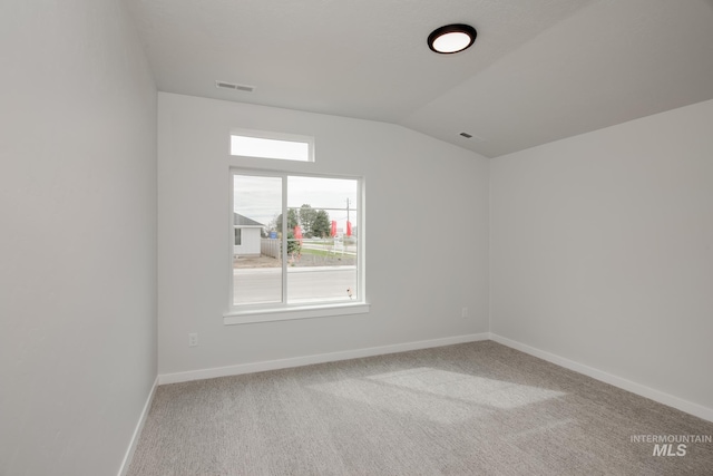 carpeted empty room featuring visible vents, baseboards, and vaulted ceiling