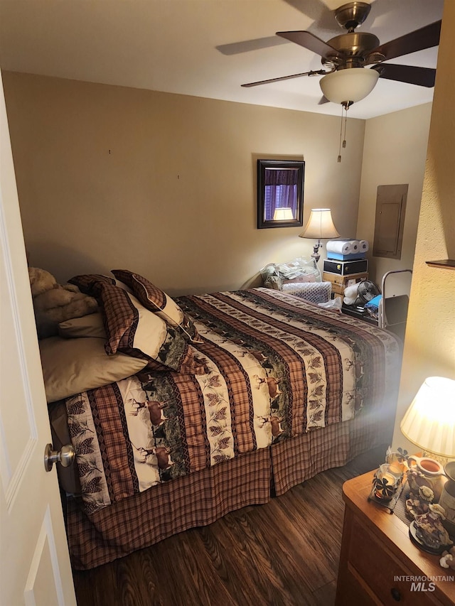 bedroom with a ceiling fan, electric panel, and wood finished floors