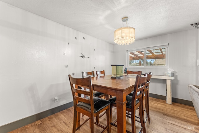 dining area featuring a notable chandelier, light hardwood / wood-style flooring, and a textured ceiling