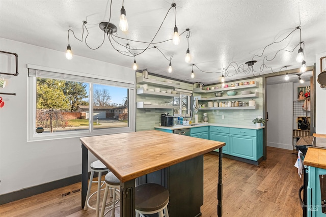 kitchen featuring light hardwood / wood-style floors, tasteful backsplash, butcher block countertops, blue cabinetry, and sink