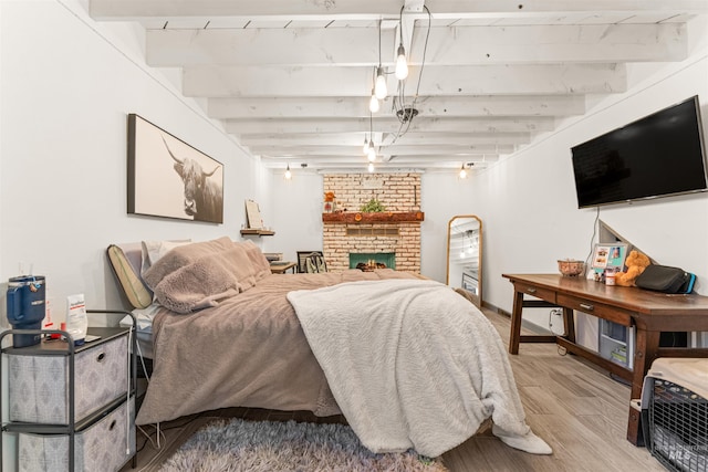 bedroom with a brick fireplace, beamed ceiling, and hardwood / wood-style floors