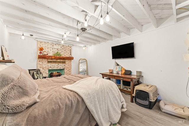 bedroom with light hardwood / wood-style floors, beamed ceiling, and a fireplace