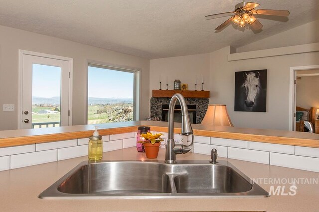 kitchen with ceiling fan, white cabinetry, sink, and vaulted ceiling