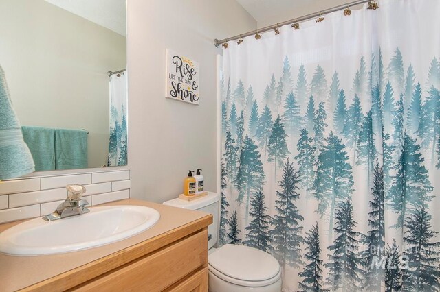 bathroom featuring vanity, backsplash, and toilet