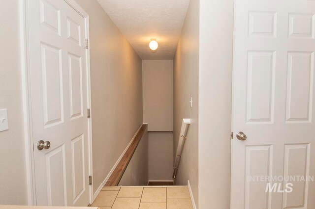 corridor with a textured ceiling and light tile floors