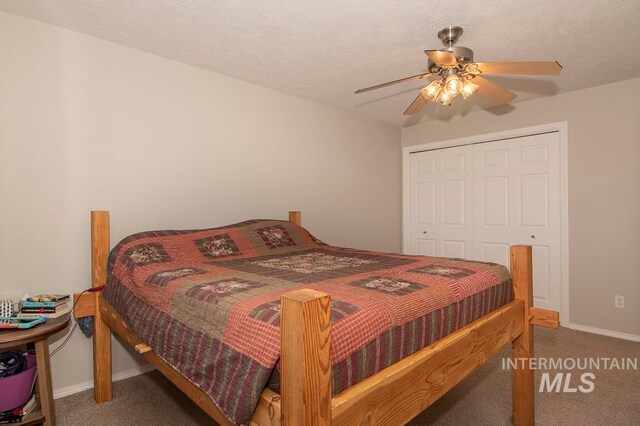 bedroom with ceiling fan, a textured ceiling, dark carpet, and a closet