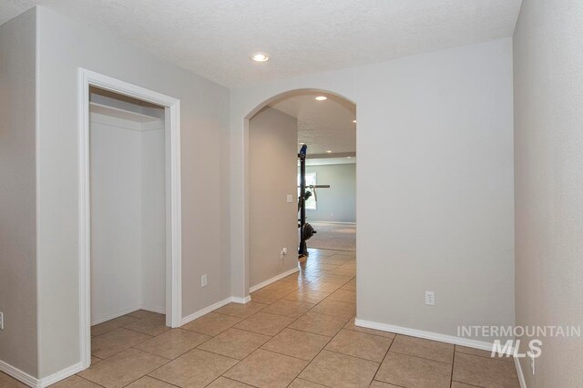 corridor with light tile floors and a textured ceiling