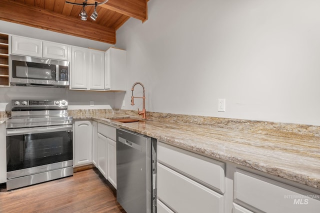 kitchen with appliances with stainless steel finishes, sink, beam ceiling, wooden ceiling, and white cabinets