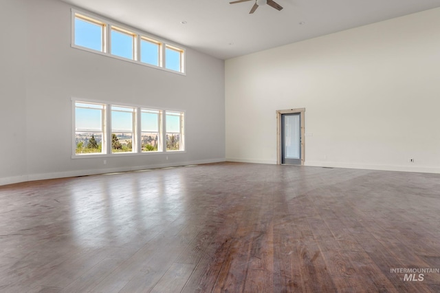 spare room with ceiling fan, a towering ceiling, and light hardwood / wood-style flooring