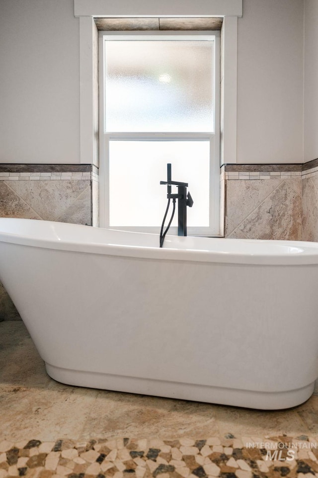 bathroom with tile walls and a tub