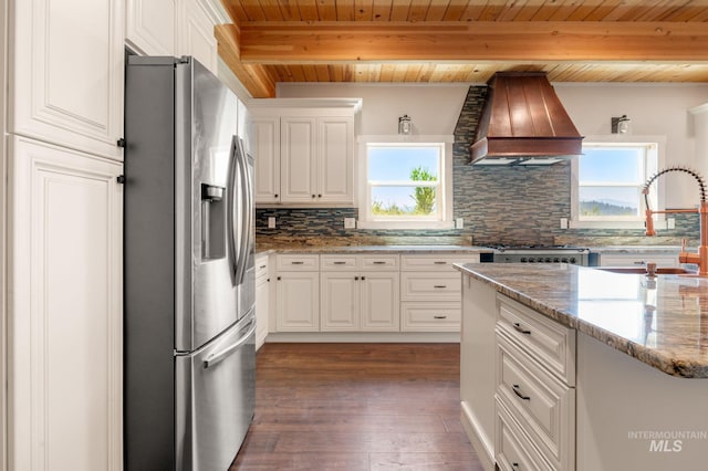 kitchen with custom exhaust hood, white cabinetry, stainless steel fridge with ice dispenser, and backsplash