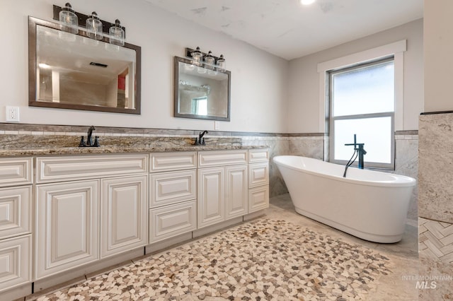 bathroom featuring tile patterned flooring, a washtub, tile walls, and vanity