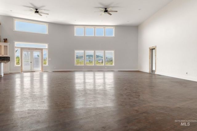 unfurnished living room with ceiling fan, french doors, dark wood-type flooring, and a high ceiling