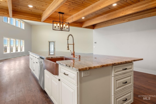 kitchen featuring hanging light fixtures, beamed ceiling, an island with sink, and wood ceiling