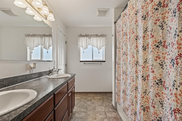 full bath with curtained shower, a sink, baseboards, and double vanity