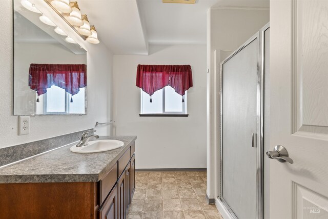 full bath featuring a stall shower, vanity, and baseboards