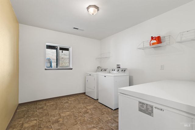 laundry area featuring washing machine and dryer, laundry area, visible vents, baseboards, and stone finish flooring