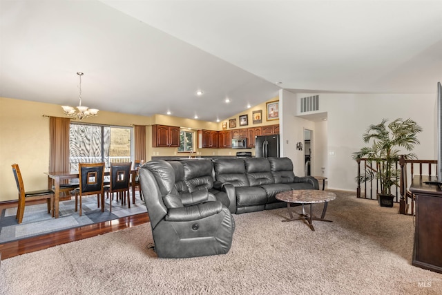 living area with lofted ceiling, visible vents, and a chandelier