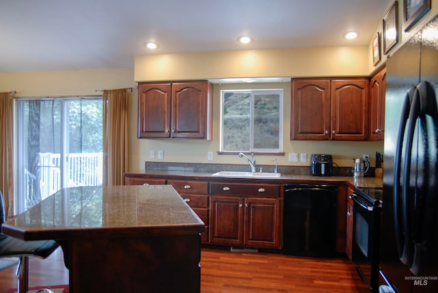 kitchen featuring a center island, sink, dark hardwood / wood-style flooring, and black appliances