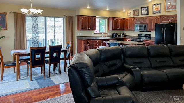 kitchen with sink, an inviting chandelier, black appliances, decorative light fixtures, and vaulted ceiling