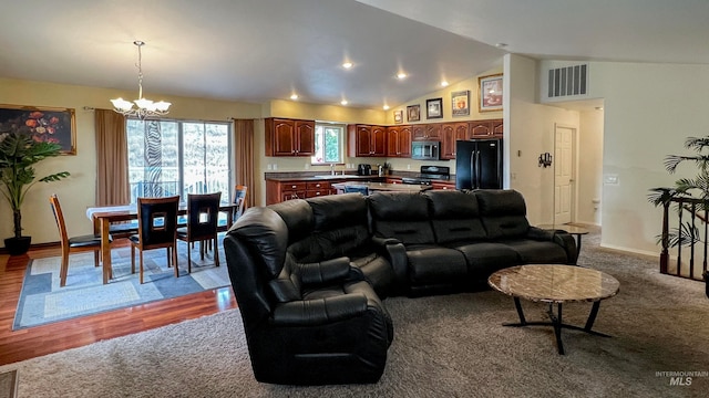 living room featuring sink, vaulted ceiling, light hardwood / wood-style flooring, and a notable chandelier