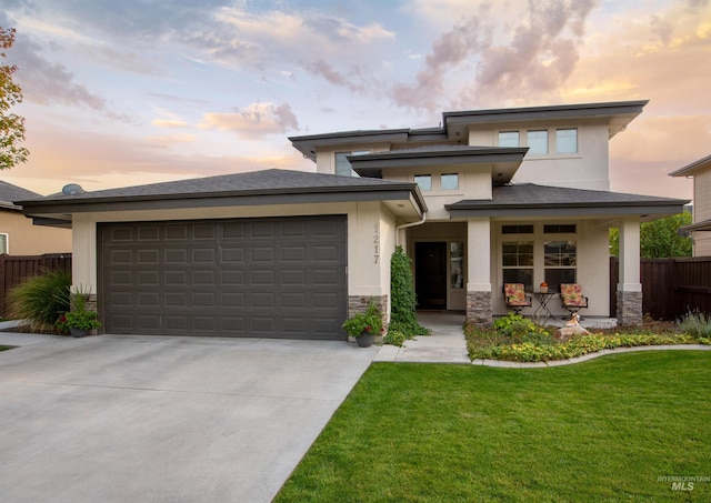 prairie-style home with a porch, a yard, and a garage