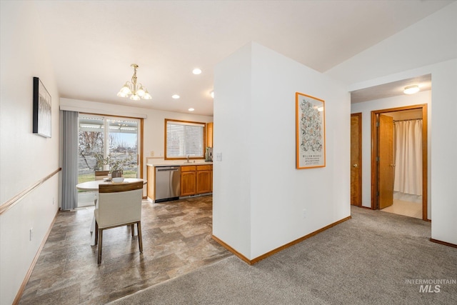 kitchen with carpet, light countertops, stainless steel dishwasher, a chandelier, and baseboards