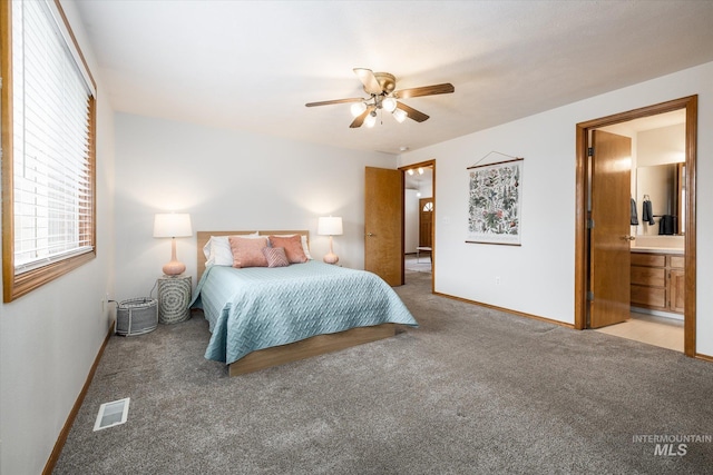 carpeted bedroom featuring visible vents, ceiling fan, ensuite bath, and baseboards