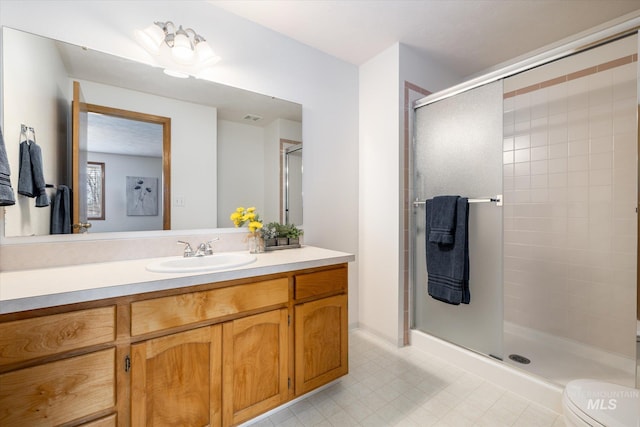 bathroom featuring toilet, a stall shower, and vanity