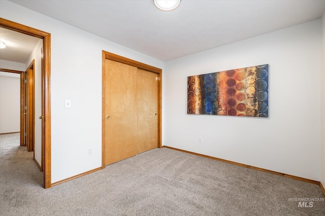 unfurnished bedroom with carpet floors, baseboards, and a closet