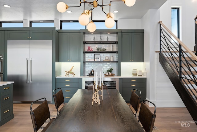 kitchen featuring decorative light fixtures, hardwood / wood-style floors, appliances with stainless steel finishes, and backsplash