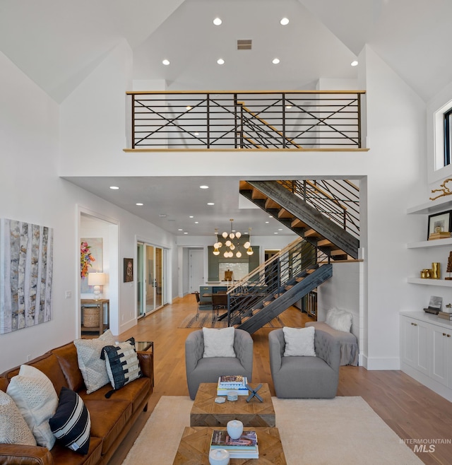 living room with high vaulted ceiling, a chandelier, and light hardwood / wood-style floors