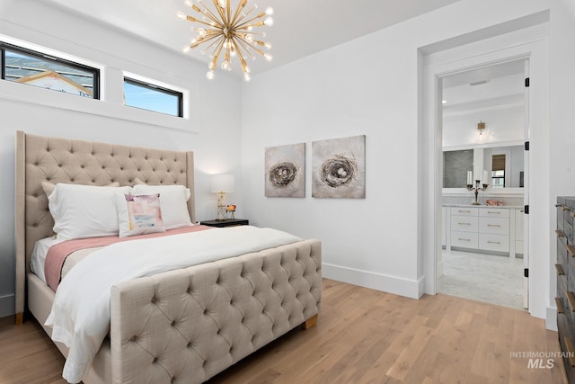 bedroom featuring light hardwood / wood-style flooring, connected bathroom, and a chandelier