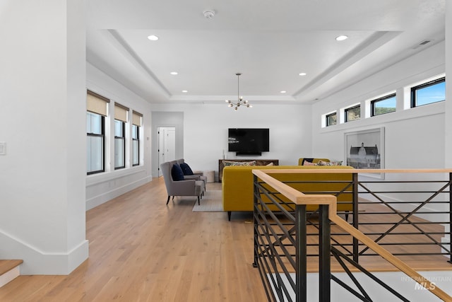 dining area with light hardwood / wood-style floors, a raised ceiling, and a chandelier