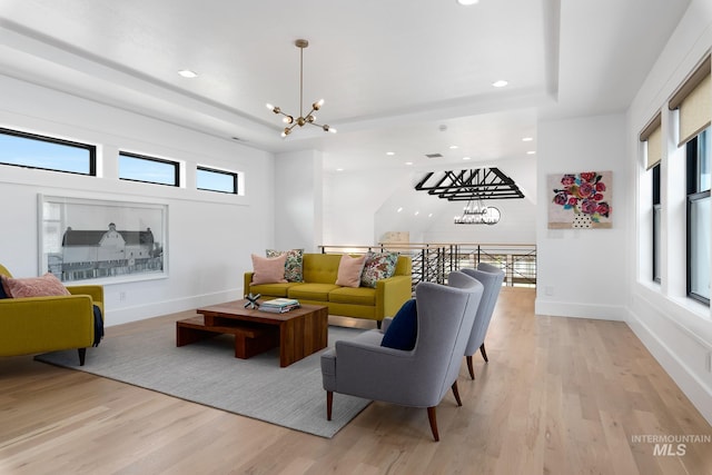 living room with a wealth of natural light, a chandelier, and light hardwood / wood-style floors