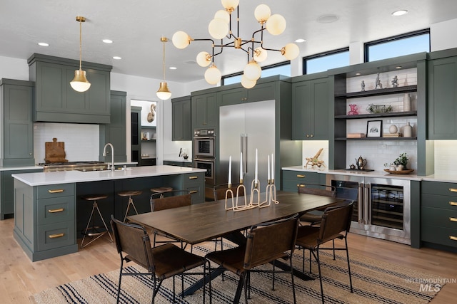 dining area featuring beverage cooler, a chandelier, light hardwood / wood-style floors, and sink