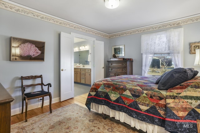 bedroom featuring sink, ensuite bath, and light hardwood / wood-style floors