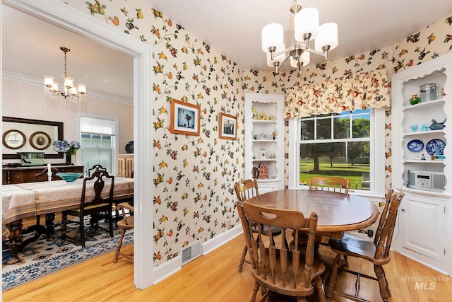 dining area featuring ornamental molding, light wood-type flooring, and a chandelier