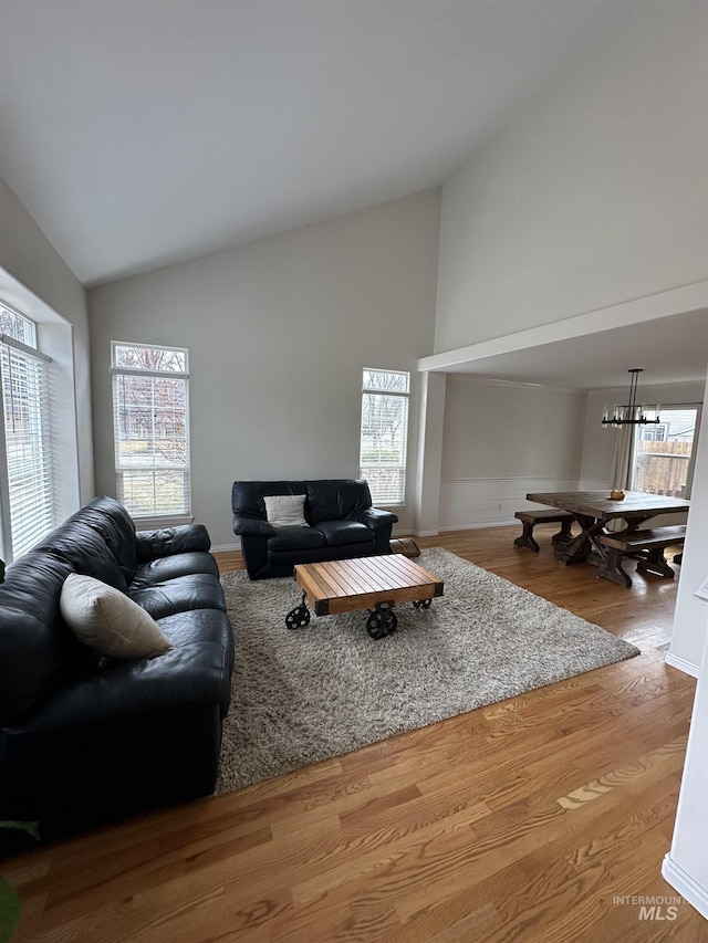 living area featuring a chandelier, wood finished floors, and high vaulted ceiling