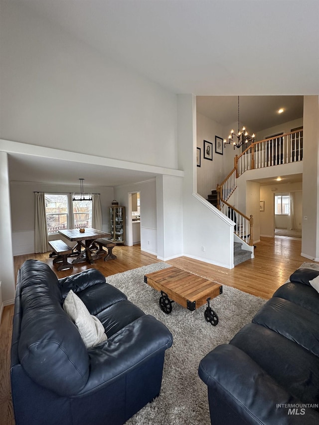 living room featuring wood finished floors, a high ceiling, an inviting chandelier, and stairway