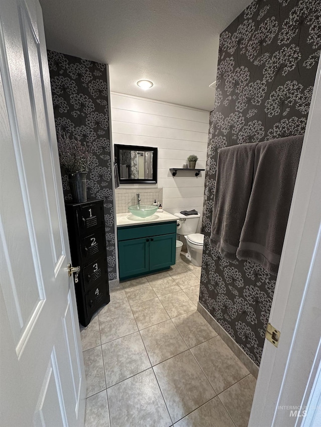 bathroom with toilet, vanity, tile patterned floors, and wallpapered walls