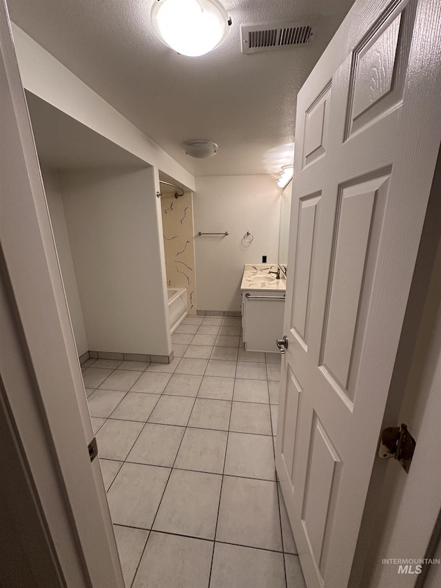 full bathroom with a textured ceiling, vanity, tile patterned flooring, visible vents, and bathing tub / shower combination