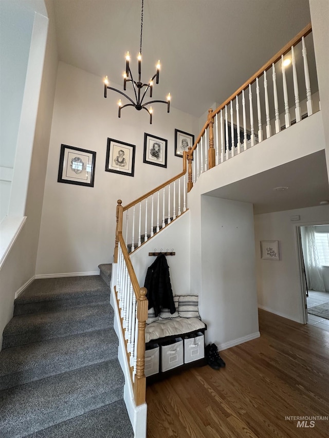 staircase with baseboards, wood finished floors, and a chandelier