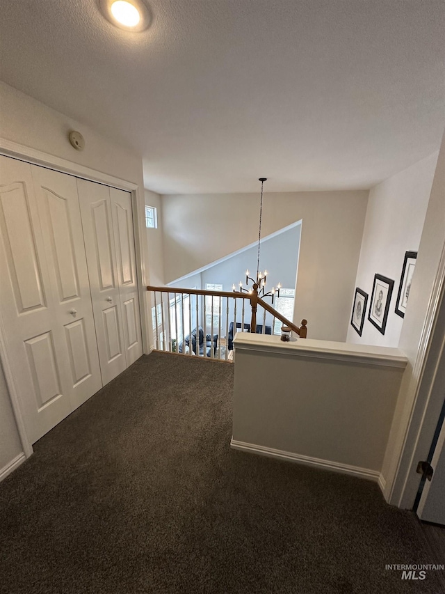 corridor featuring an upstairs landing, carpet, and a notable chandelier