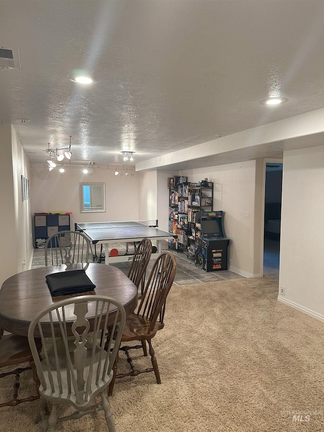 carpeted dining area with a textured ceiling, rail lighting, baseboards, and visible vents
