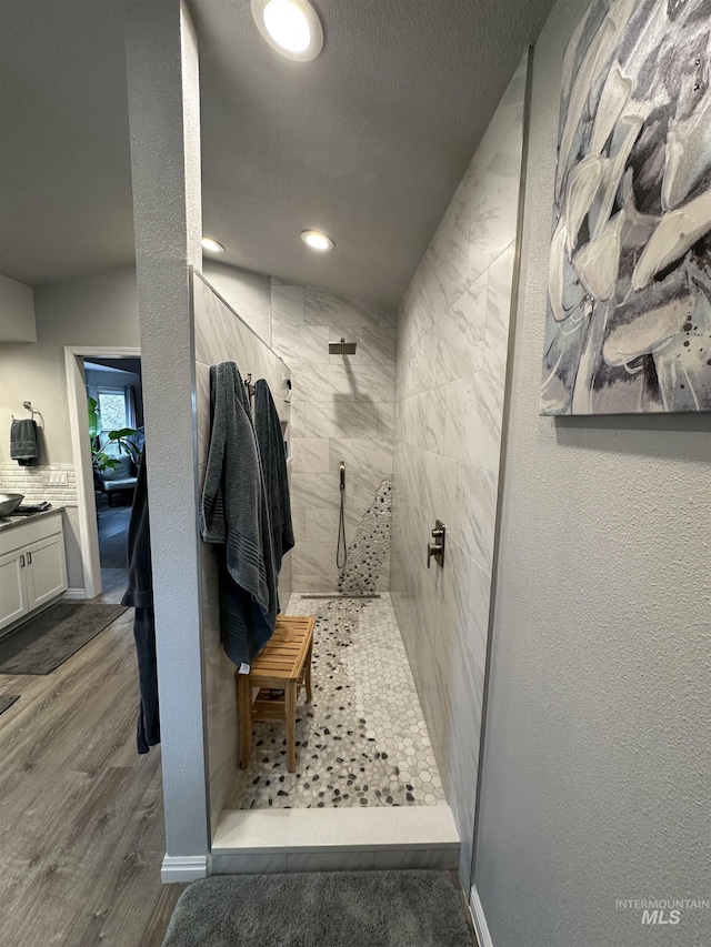 full bathroom with recessed lighting, vanity, wood finished floors, and tiled shower