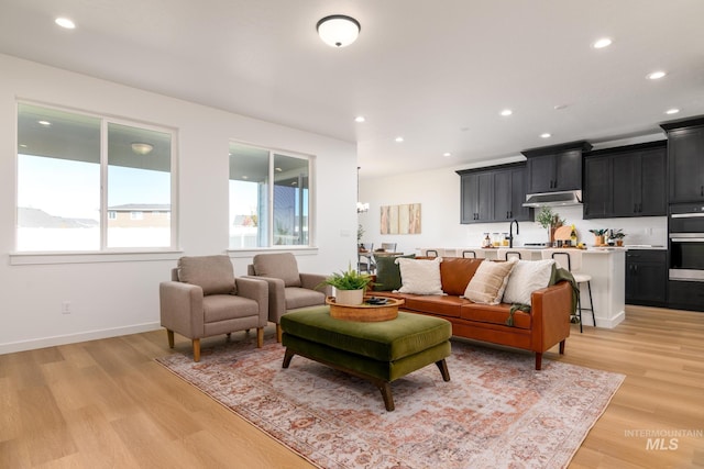 living room with baseboards, recessed lighting, and light wood-style floors